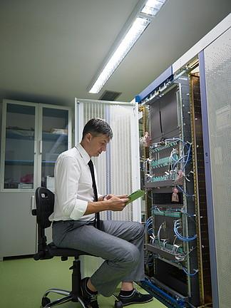 网络工程师在服务器机房工作在平板电脑上的公司业务人工作
